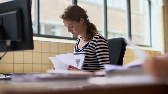 Female architect looking at blueprints in office