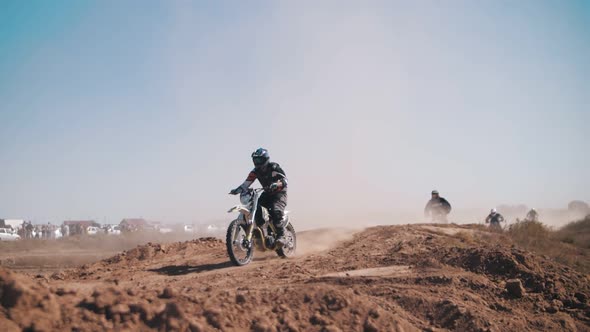Skilled motocross rider on a sandy track, performing stunts on motorcycles, moto festival.