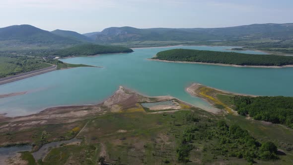 Aerial View on Water Reservoir at Mountain Valley Covered with Green Spring Forest alt