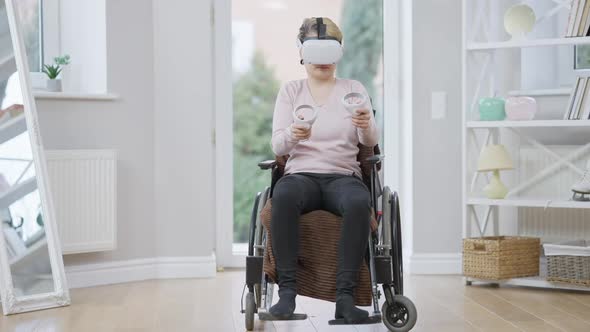 Wide Shot Portrait of Handicapped Young Woman in Wheelchair Playing Video Game in Slow Motion alt