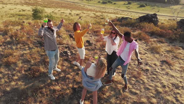 Happy Friends are Standing in Field and Drinking Cocktails