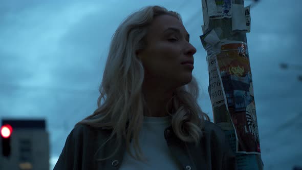 Attractive Girl Looking Up at Evening City in Urban Background alt