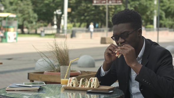 Afro-american businessman eating meal during lunch time in cafe