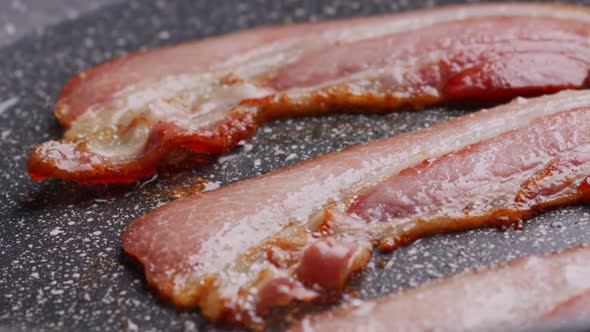 Pieces of Crispy Flavorful Bacon Fried in Pan alt