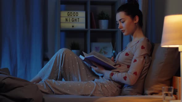 Teenage Girl Reading Book in Bed at Night