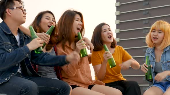 Group of Asian young people clinking bottles of beer party on the rooftop.