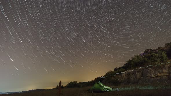Startrails with polaris in circles over tent in croatian landscape at night alt