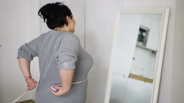 Young Overweight Woman Feeling Happy After Measuring Her Waist at Home alt