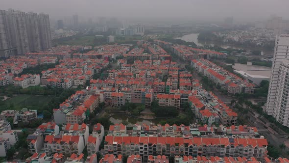 Foggy,smoggy early morning drone footage over urban high-rise and villa housing developments in dist alt