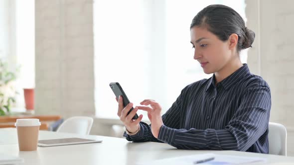 Young Indian Woman Celebrating Success on Smartphone alt