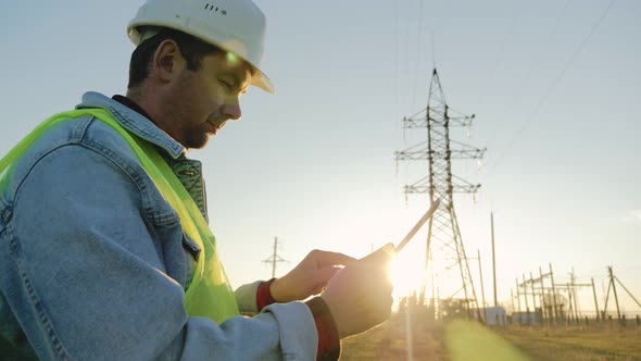 Engineer Standing on Field with Electricity Towers alt