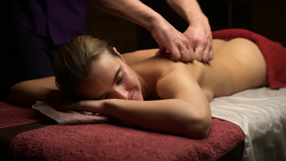 Young beautiful woman enjoying relaxing massage in the salon of masseur alt