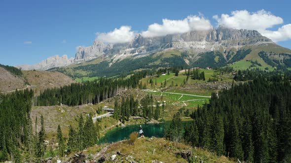 Women on Top of Hill with Uprooted Pine Trees After Strong Wind in Lake Carezza Most Beautiful Lakes alt