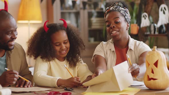 Happy Black Family Making Halloween Decorations and Playing alt