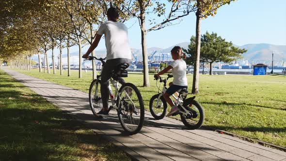 Mother and daughter is riding a bike along the seafront together, steadicam shot alt