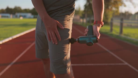 An Athlete Massages with a Percussion Therapy Gun to Relieve the Pain of Muscle Aches After a alt