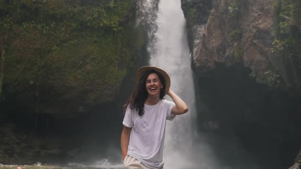 Girl in a Straw Hat on a Background of a Waterfall