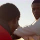Black man in sportswear is boxing with his trainer outdoors, front view. Trainer is engaged - VideoHive Item for Sale