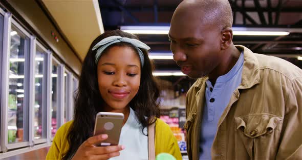 Couple using mobile phone while shopping alt