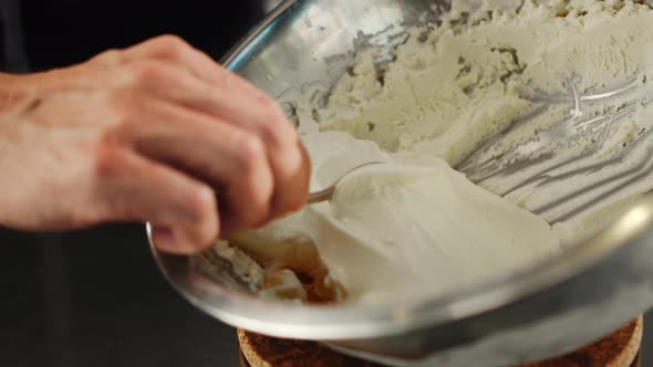 Professional kitchen, close-up: ice cream is scooped into a spoon from a bowl alt