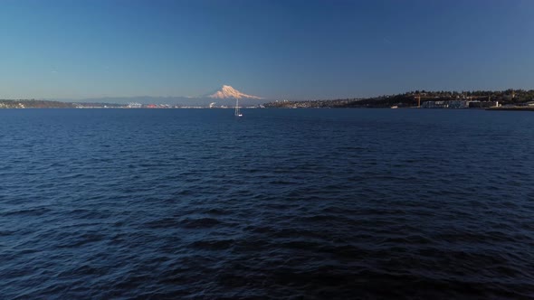 A lone sail boat in Commencement Bay of the shore of Tacoma Washington, Mount Rainier and the tide f alt