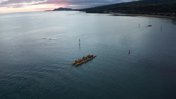 Descending aerial shot of an outrigger canoe rowing on the ocean in O'ahu, Hawaii. 4K alt