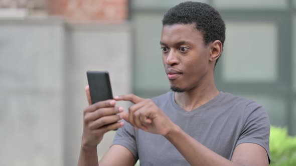 Portrait of Excited Young African Man Celebrating on Smartphone  alt