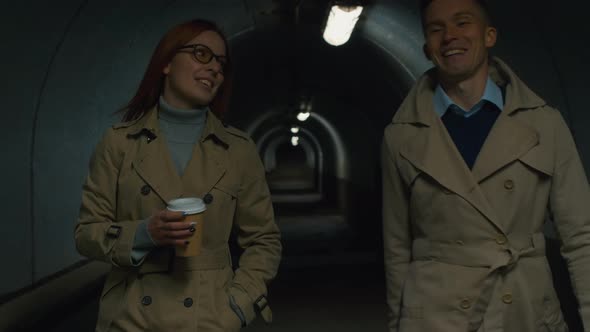 Smiling man and a woman with rolling-bag going through the tunnel