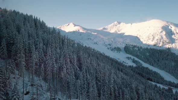 Aerial Footage Of Woods  SnowCapped Mountains With Peaks Touching Clear Blue Sky alt