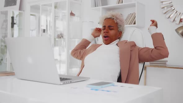 Attractive African American Woman Pulls Up and Yawns While Working with Laptop alt