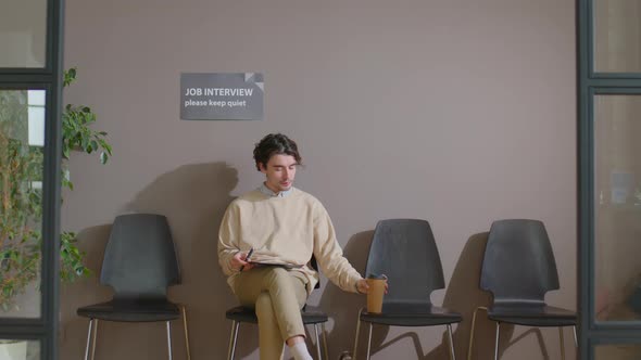 Young Man Drinking Coffee while Waiting for Job Interview alt