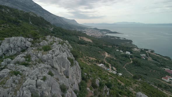 Aerial View of the Town of Makarska in Croatia with a Large Rocky Cliff in the Frame