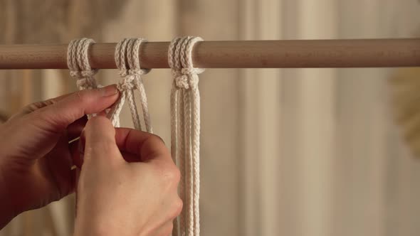 A Woman Craftsman Weaves Macrame From Light Cotton Threads in Her Home Workshop alt