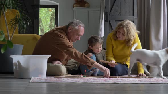 grandparents play the railway with their grandson at home.