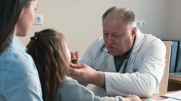 Pediatrician examining little child's throat