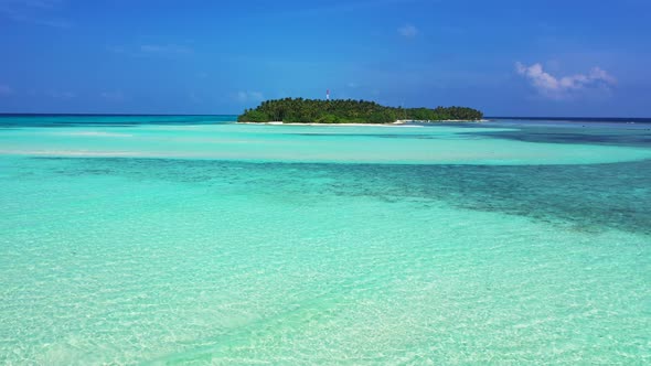 Wide above island view of a sandy white paradise beach and blue water background in colorful 4K alt