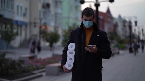 Men Walking in Medical Mask with Toilet Paper and Smartphone During the Second Wave Quarantine alt
