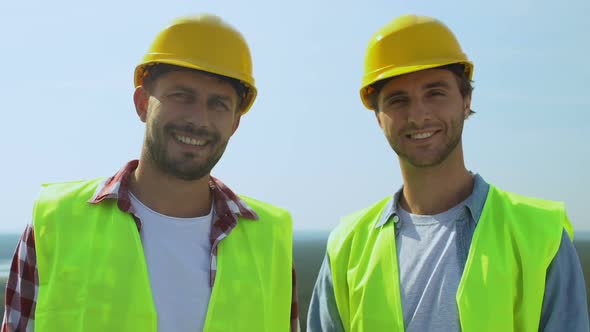 Experienced Male Builders in Helmets and Uniform Smiling on Camera, Good Service