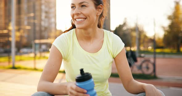 Beautiful Sportswoman Drinking Water and Hydrating After Jogging