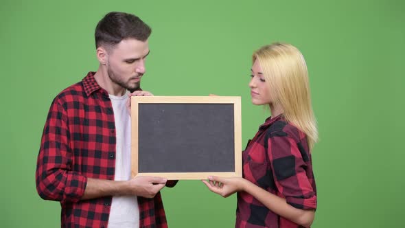 Young Couple Holding Blackboard Together
