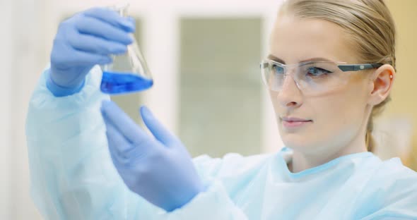Female Scientist with a Pipette Analyzes a Liquid at Laboratory alt