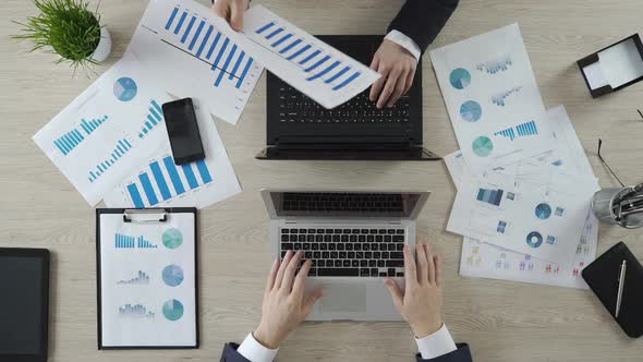 Hands of Colleagues Working on Laptops, Discussing Company Statistics, Top View alt