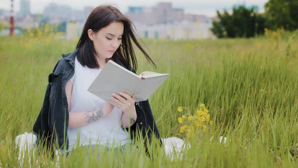 Concentrated Woman Caucasian Brunette Girl Sits on Grass Reads Book Educational Literature Novel alt