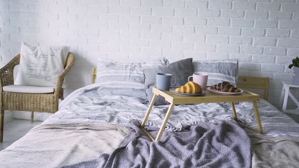 Small Table with Coffee and Croissants on Large Bed in Flat