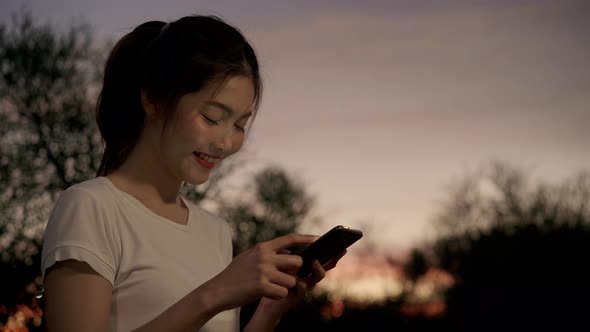 Asian tourist blogger woman using touchscreen technology at smartphone while walking. alt