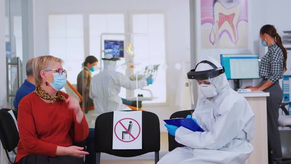 Dentist with Face Shield Talking with Elderly Woman Before Examination alt