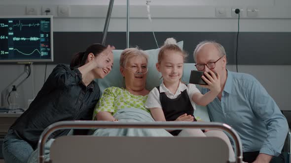 Family Taking Pictures with Old Patient in Hospital Ward alt