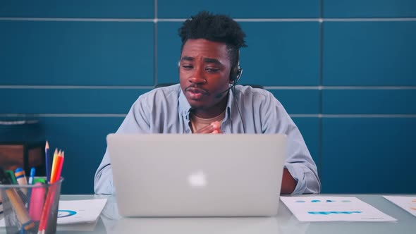 African American Man Executive Wears Headset Video Calling on Laptop alt