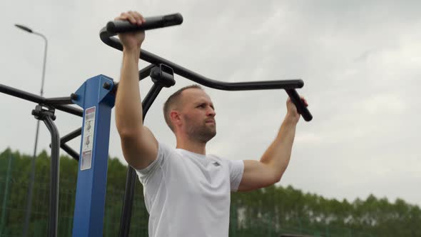 Male Bodybuilder Performing Exercises with a Heavy Weight for the Back on a Simulator on an Outdoor alt