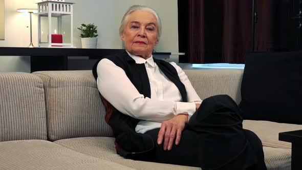 Old Caucasian Woman Looks To Camera with Serious Face in Living Room alt